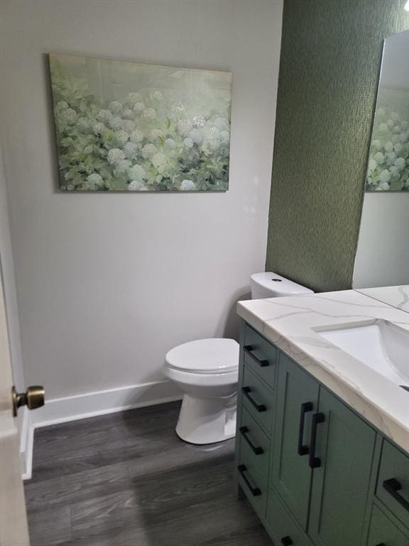 bathroom with wood-type flooring, vanity, and toilet