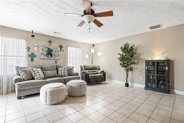 living room featuring light tile patterned floors, a textured ceiling, ceiling fan, and a healthy amount of sunlight