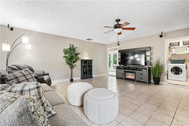 tiled living room featuring ceiling fan, washer / dryer, and a textured ceiling