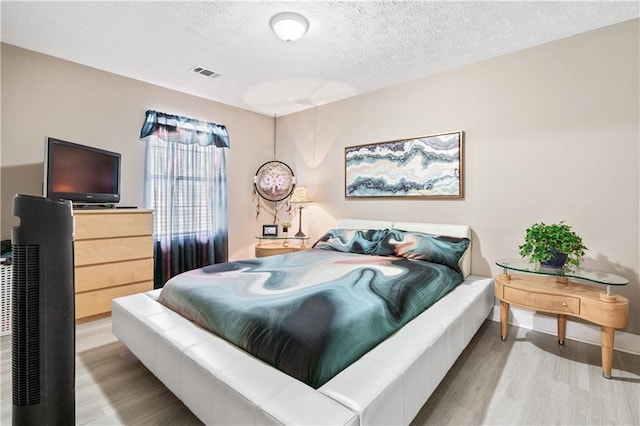 bedroom featuring a textured ceiling and light hardwood / wood-style flooring