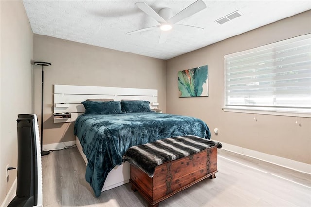 bedroom with ceiling fan, a textured ceiling, and light hardwood / wood-style flooring