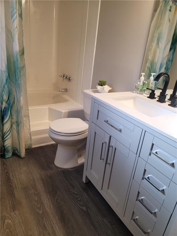 full bathroom featuring wood-type flooring, vanity, toilet, and shower / bathtub combination with curtain