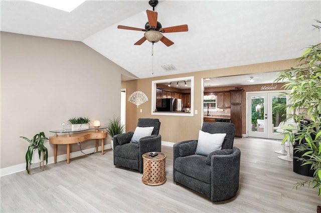 living room featuring ceiling fan, french doors, light hardwood / wood-style floors, and vaulted ceiling