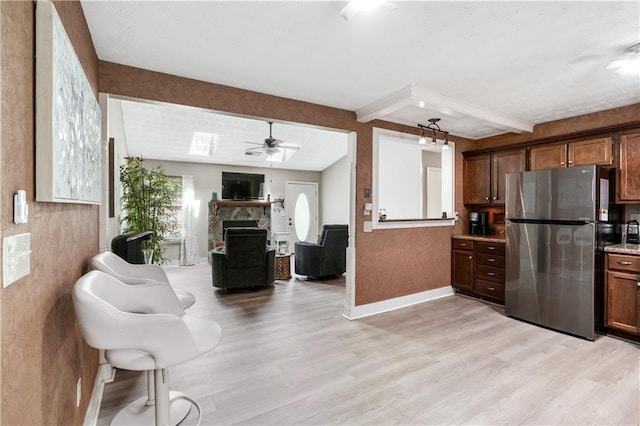 kitchen featuring ceiling fan, stainless steel fridge, beam ceiling, and light hardwood / wood-style flooring