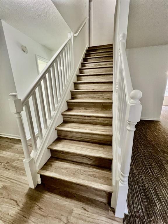 stairway with baseboards and a textured ceiling