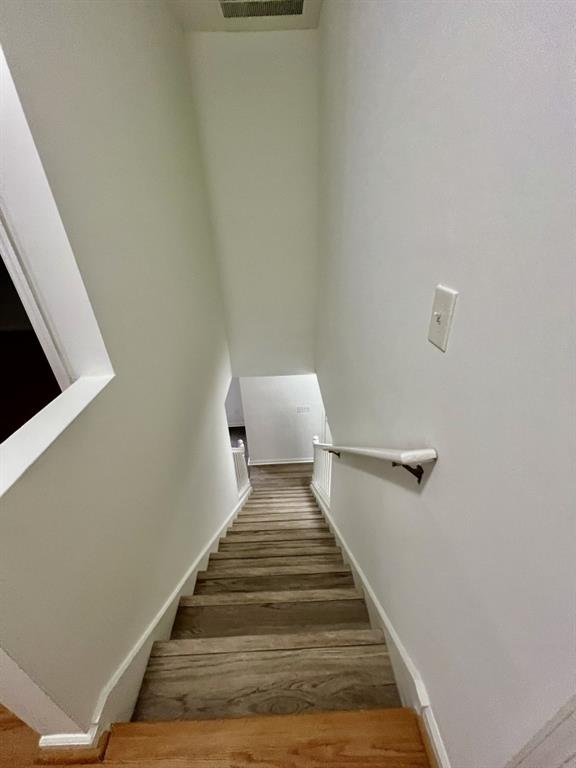 staircase featuring visible vents, wood finished floors, and baseboards