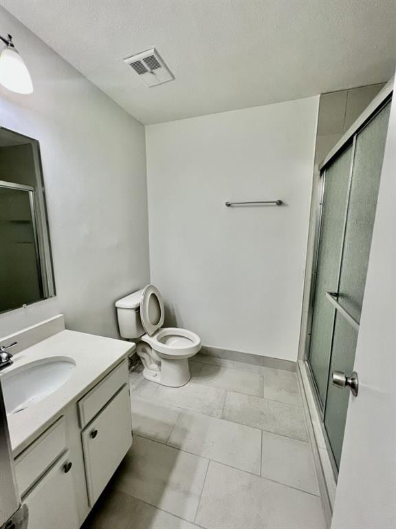 full bath featuring a shower with door, visible vents, toilet, vanity, and a textured ceiling