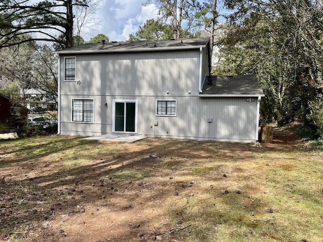 rear view of house featuring a patio and a shingled roof