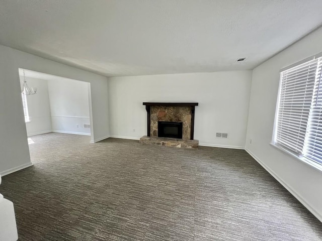 unfurnished living room with visible vents, a stone fireplace, baseboards, and carpet floors