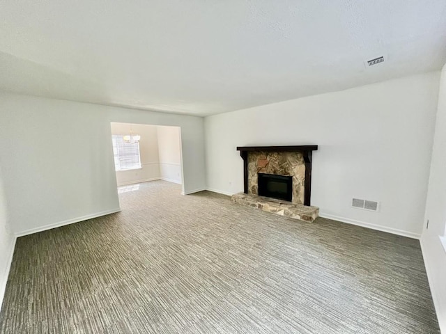 unfurnished living room with a notable chandelier, a fireplace, visible vents, and baseboards