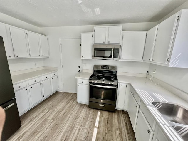 kitchen with light wood-style flooring, white cabinets, and stainless steel appliances