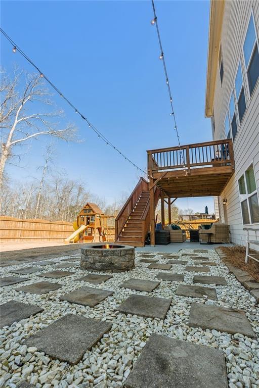 view of yard featuring a patio area, stairs, a playground, and fence