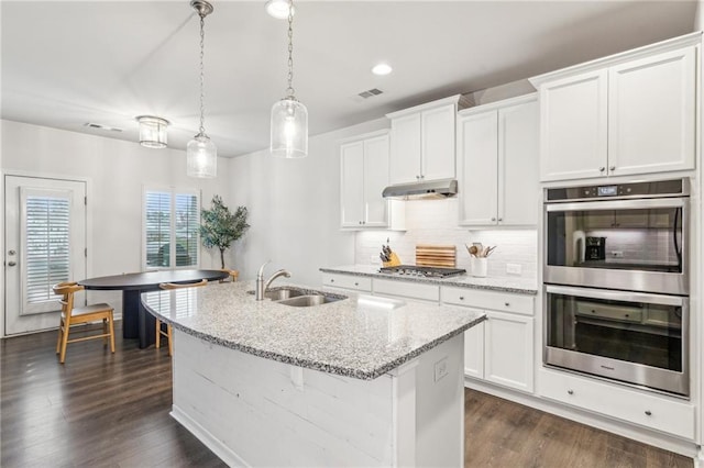 kitchen with tasteful backsplash, visible vents, under cabinet range hood, stainless steel appliances, and a sink