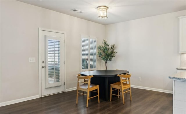 dining space with dark wood-type flooring, a notable chandelier, baseboards, and visible vents