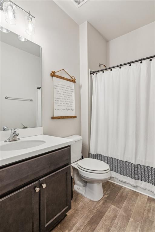 bathroom featuring vanity, a shower with curtain, toilet, and wood finished floors