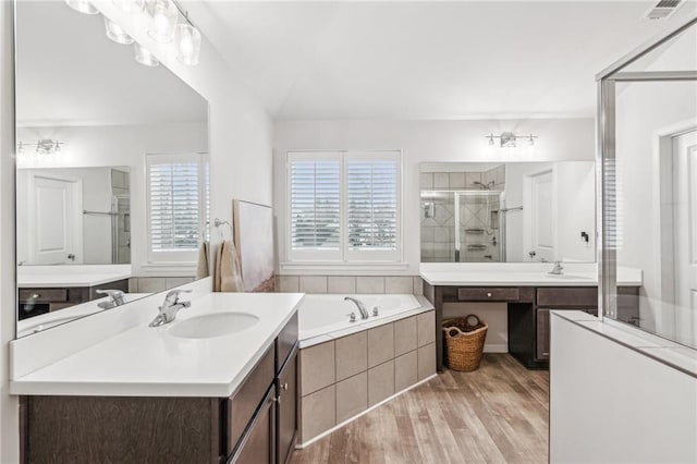 bathroom with wood finished floors, visible vents, a stall shower, a sink, and a bath