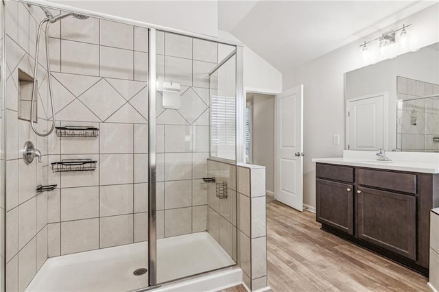 bathroom with vanity, lofted ceiling, wood finished floors, and a stall shower