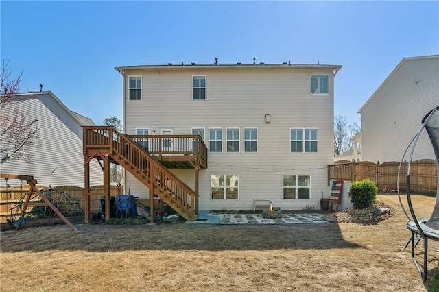 back of house with a trampoline, stairway, a fenced backyard, a yard, and a patio