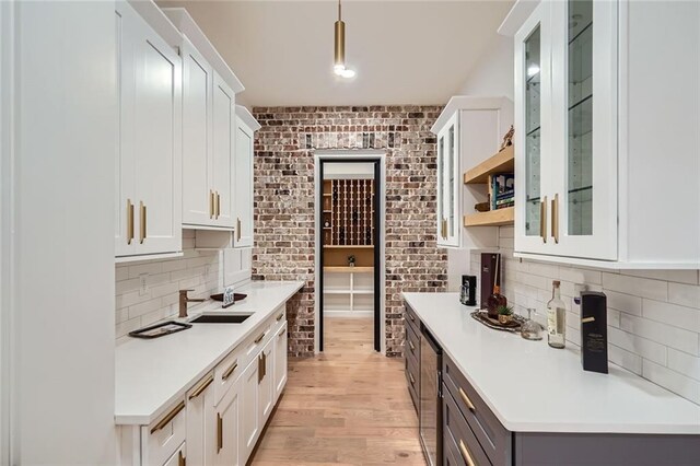 2625 Beverly Ln, Snellville, GA 30078 - kitchen featuring a sink, light countertops, white cabinetry, and brick wall