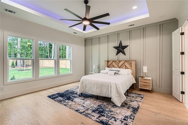 2625 Beverly Ln, Snellville, GA 30078 - bedroom featuring multiple windows, a decorative wall, light wood-style flooring, a raised ceiling, and a ceiling fan