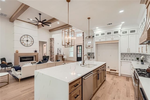 2625 Beverly Ln, Snellville, GA 30078 - kitchen featuring a sink, stainless steel appliances, a glass covered fireplace, light wood-type flooring, and ceiling fan