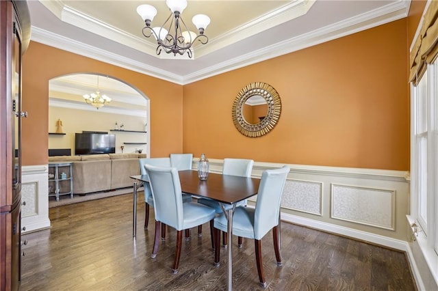 dining space with ornamental molding, a tray ceiling, a notable chandelier, and wood finished floors