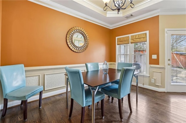 dining room with visible vents, a wainscoted wall, ornamental molding, wood finished floors, and an inviting chandelier