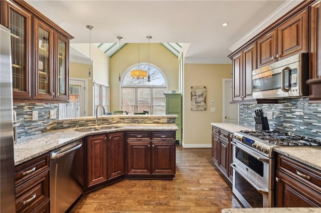 kitchen featuring a peninsula, stainless steel appliances, crown molding, pendant lighting, and a sink