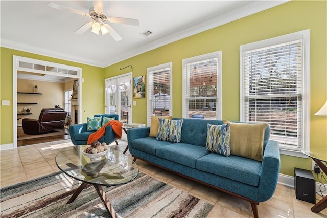 living room featuring baseboards, visible vents, a ceiling fan, ornamental molding, and tile patterned floors