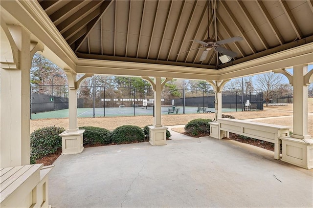 view of patio featuring a tennis court, fence, a ceiling fan, and a gazebo