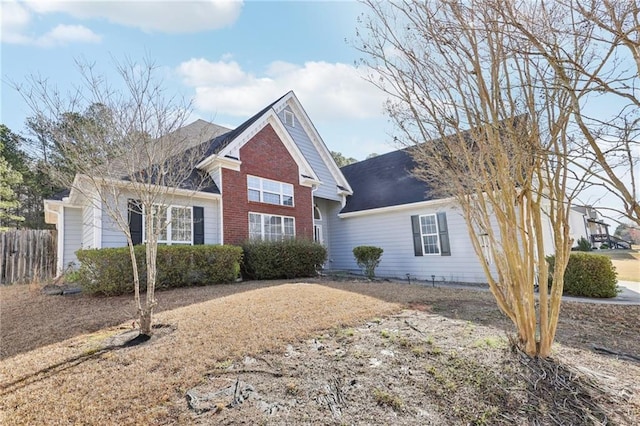 view of front of house featuring brick siding and fence