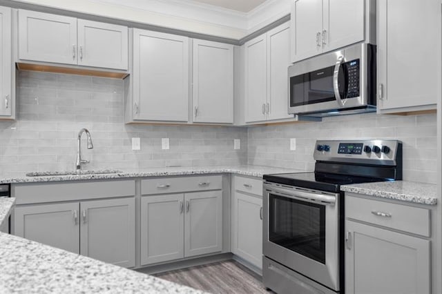 kitchen featuring light stone counters, stainless steel appliances, sink, and gray cabinetry