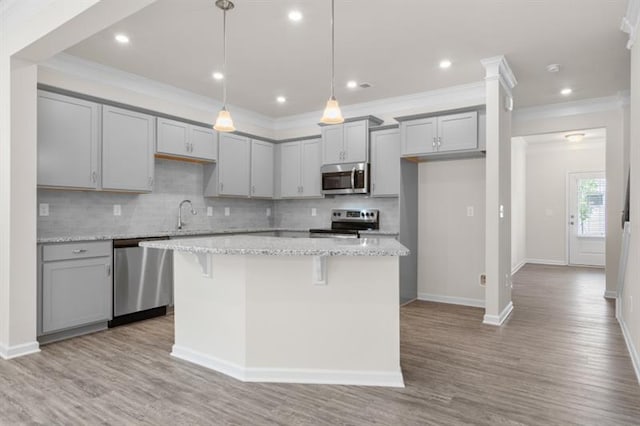 kitchen featuring pendant lighting, stainless steel appliances, light stone countertops, and a kitchen island