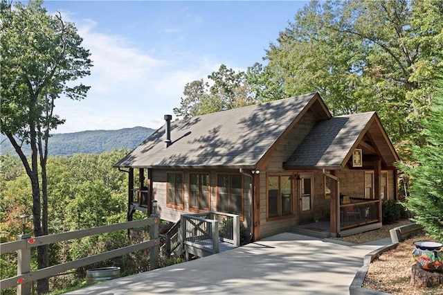 view of front of home featuring stone siding, a shingled roof, and a mountain view