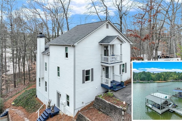 view of side of home featuring a water view, a dock, and a balcony