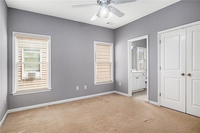 unfurnished bedroom featuring visible vents, baseboards, a closet, ensuite bathroom, and light colored carpet