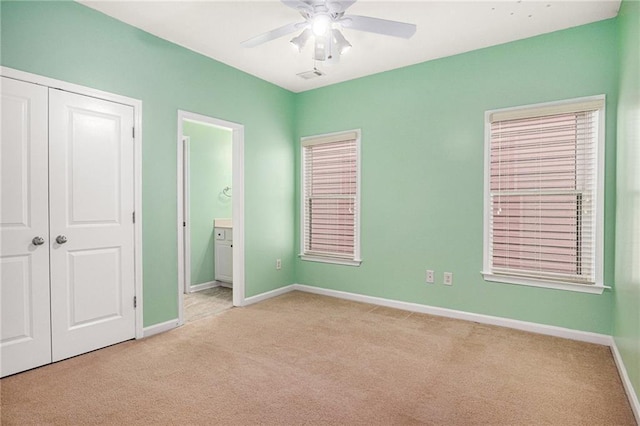 unfurnished bedroom featuring visible vents, baseboards, light carpet, ensuite bathroom, and a closet