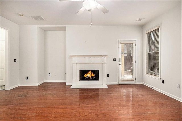 unfurnished living room featuring a lit fireplace, visible vents, a ceiling fan, and wood finished floors