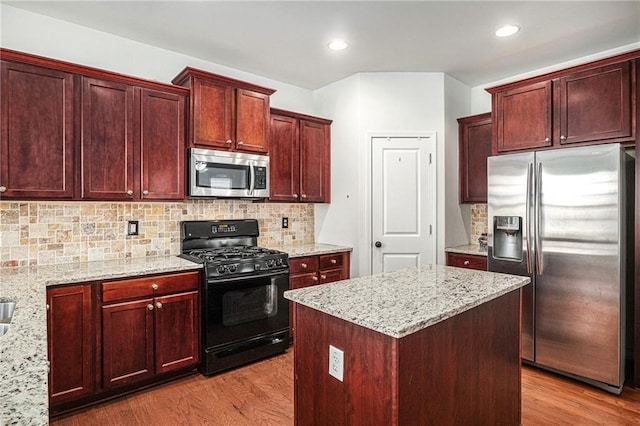 kitchen with stainless steel appliances, dark brown cabinets, and wood finished floors