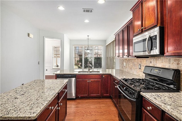 kitchen featuring visible vents, light wood-type flooring, decorative backsplash, appliances with stainless steel finishes, and a sink