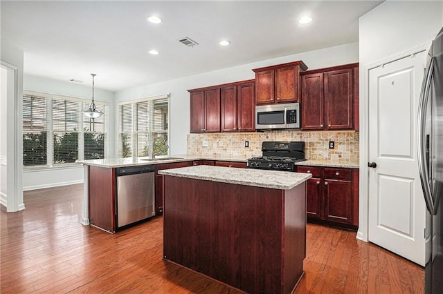 kitchen featuring visible vents, a sink, a kitchen island, appliances with stainless steel finishes, and a peninsula