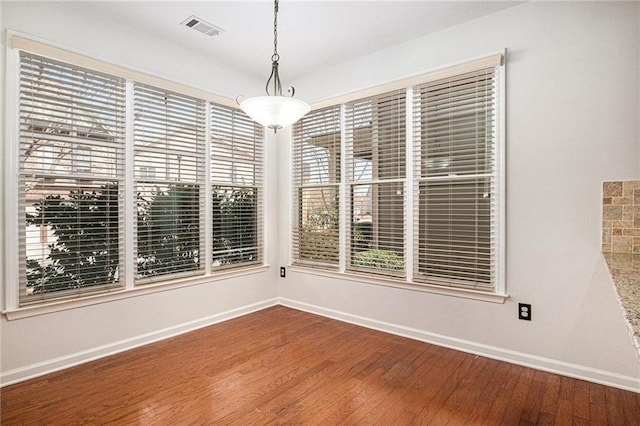 unfurnished room with visible vents, baseboards, and wood finished floors