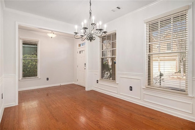 empty room featuring wood finished floors, a wainscoted wall, visible vents, an inviting chandelier, and crown molding