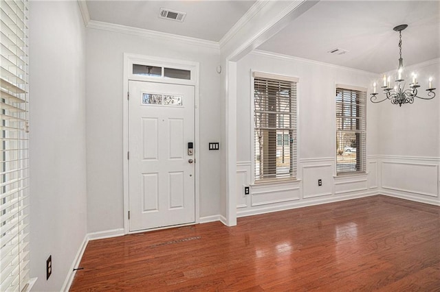 foyer featuring visible vents, a notable chandelier, wood finished floors, wainscoting, and crown molding