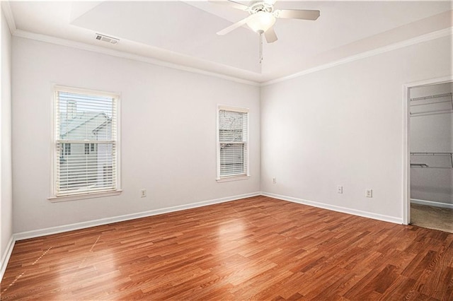 unfurnished bedroom with a raised ceiling, crown molding, wood finished floors, and baseboards