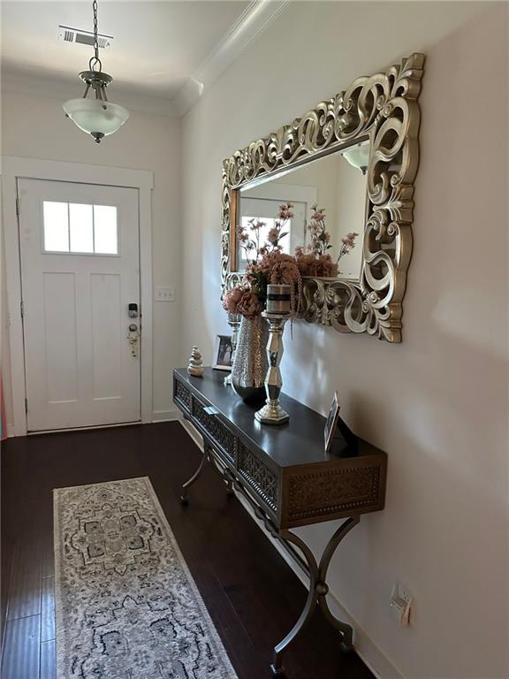 entryway featuring dark wood-type flooring and crown molding