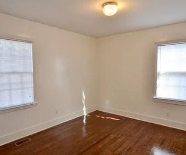 unfurnished room with visible vents, baseboards, and wood finished floors