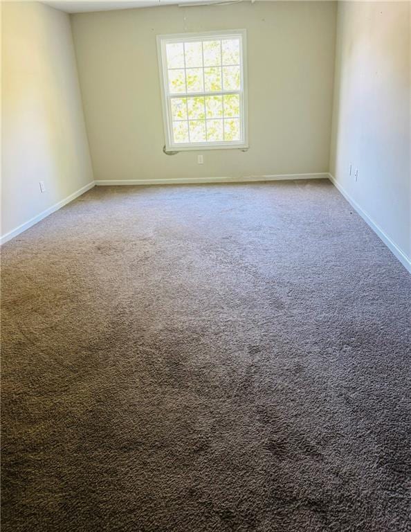 carpeted empty room featuring baseboards