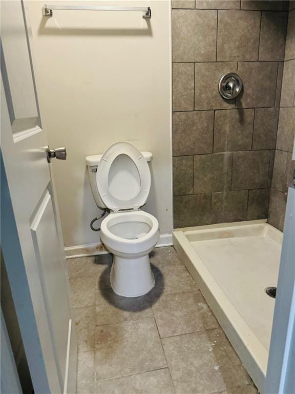 bathroom with baseboards, a shower stall, toilet, and tile patterned floors