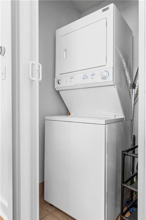 clothes washing area featuring light tile patterned floors and stacked washer / dryer